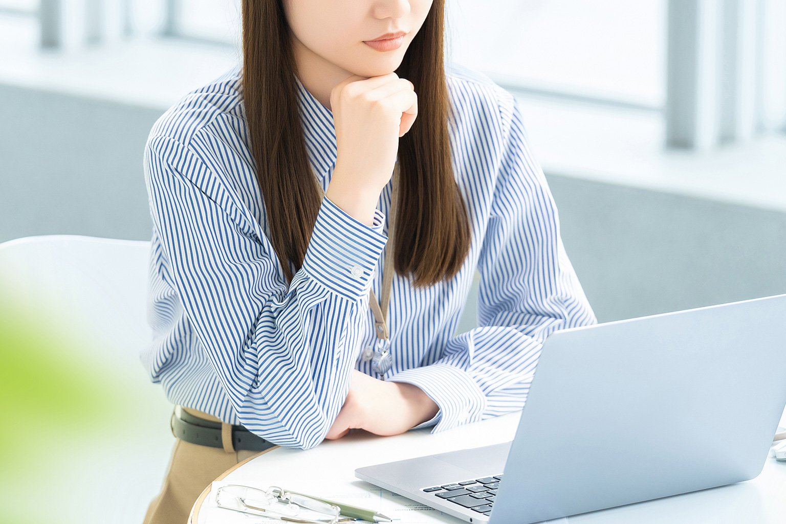 ノートパソコンの前で考え事をしている女性