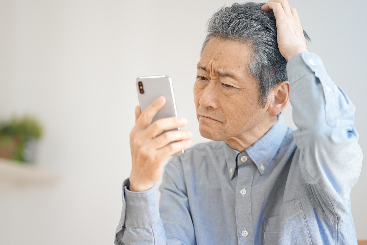 スマホを手に困っている男性