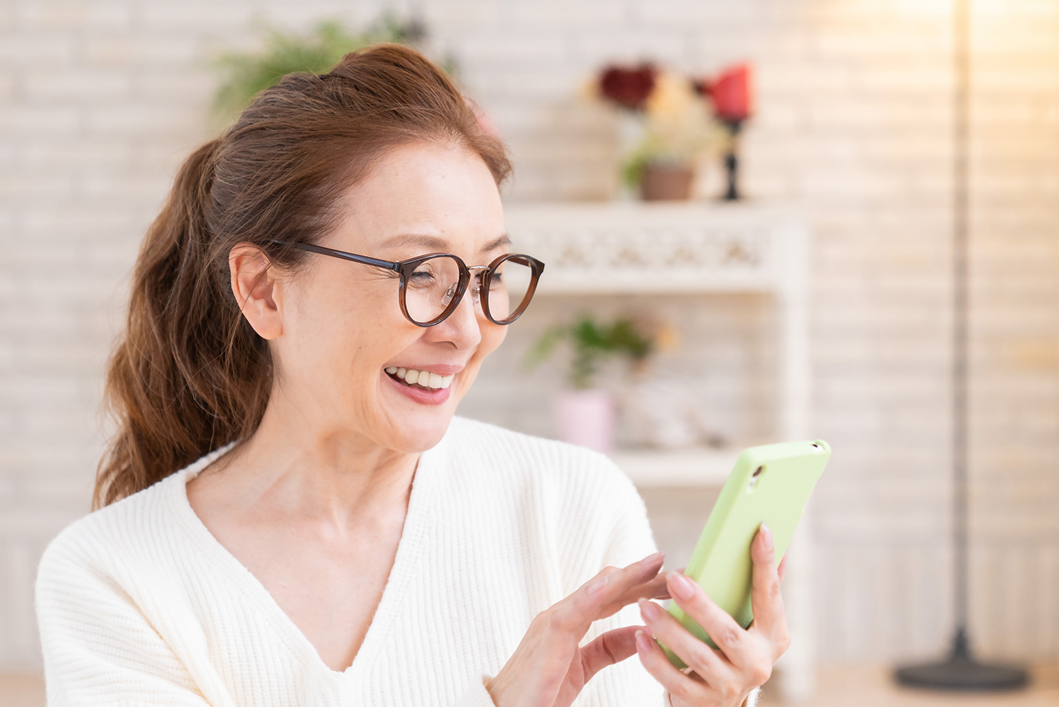 スマホを操作するメガネをかけた女性